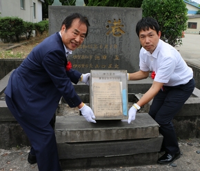 タイムカプセルを取り出す塚部市長（左）と当時誕生され石碑に名前が刻まれた立会人