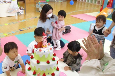 誕生日のケーキに集まる子どもたち