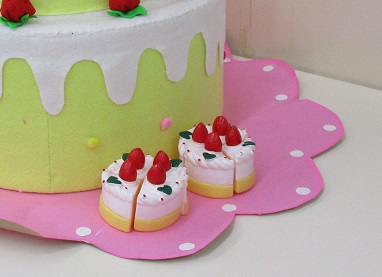 大きなケーキの横に小さなケーキを飾った子